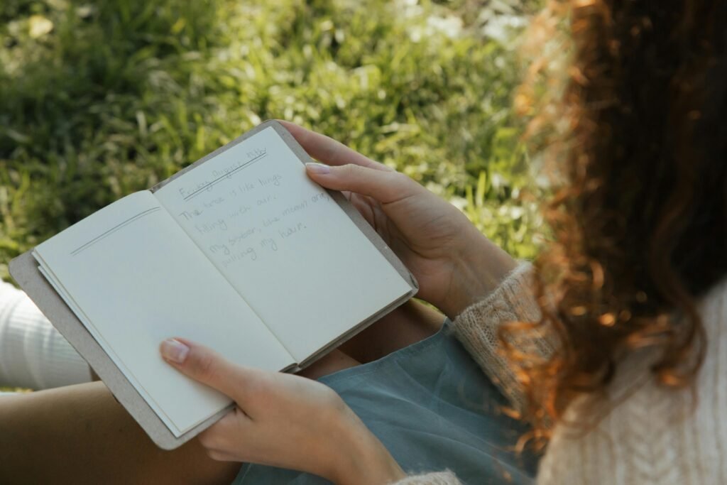 Writing in a field journal while sitting on the grass and practicing handwriting during a digital detox mission.