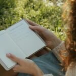 Writing in a field journal while sitting on the grass and practicing handwriting during a digital detox mission.